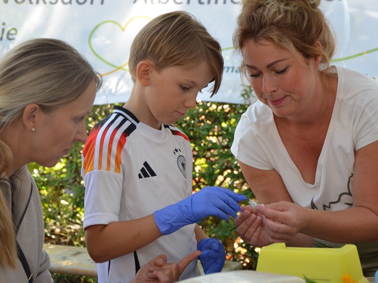 Ein Kind mit blauen Einmalhandschuhen bei einer Simulationsübung mit Mitarbeiterinnen an den Ständen des Gesundheitscampus Volksdorf der Immanuel Albertinen Diakonie beim Stadtteilfest Volksdorf in Hamburg Ein Kind mit blauen Einmalhandschuhen bei einer Simulationsübung mit Mitarbeiterinnen an den Ständen des Gesundheitscampus Volksdorf der Immanuel Albertinen Diakonie beim Stadtteilfest Volksdorf in Hamburg